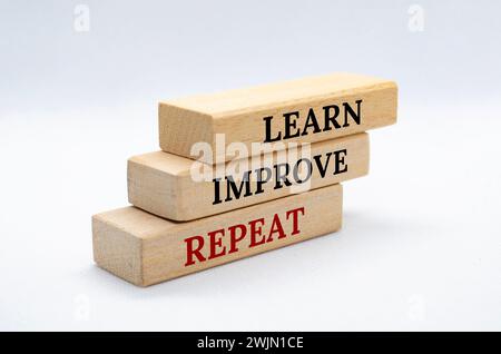 Learn, improve and repeat text on wooden blocks with white cover background. Improvement concept. Stock Photo