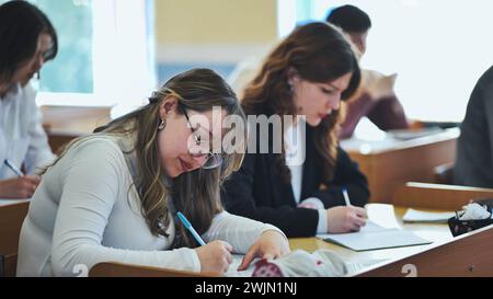 Girl students writing math formulas in a notebook. Stock Photo