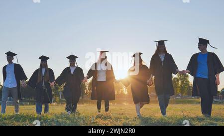 Graduate students walking through an evening meadow at sunset. Stock Photo