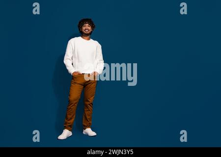 Full body length size photo of wavy hair in white pullover and brown pants posing billboard ad isolated on dark blue color background Stock Photo