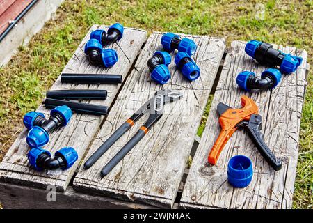 Compression fittings for connecting HDPE pipes lie on table next to hand tools. Stock Photo