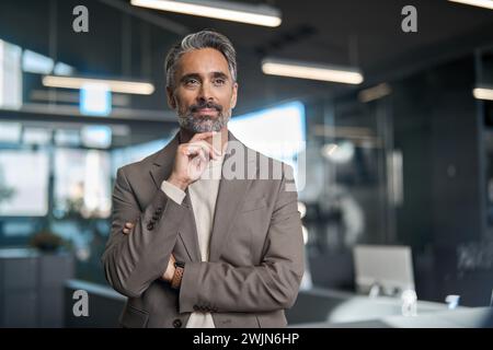 Serious mature business man investor standing in office thinking looking away. Stock Photo
