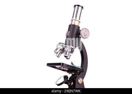 an old microscope stands isolated on a white background on a white surface with real shadows Stock Photo