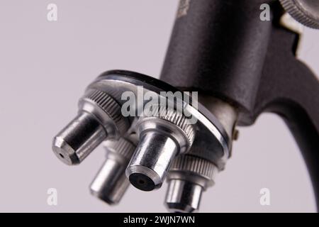 an old microscope stands on a white surface with real shadows, close up Stock Photo
