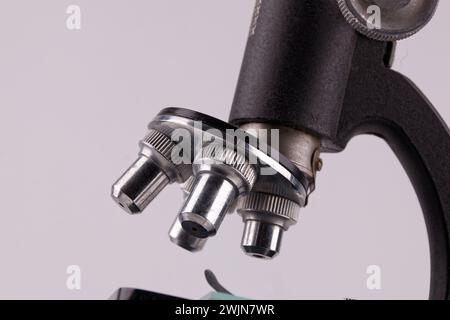 an old microscope stands on a white surface with real shadows, close up Stock Photo