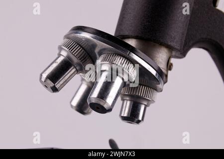 an old microscope stands on a white surface with real shadows, close up Stock Photo