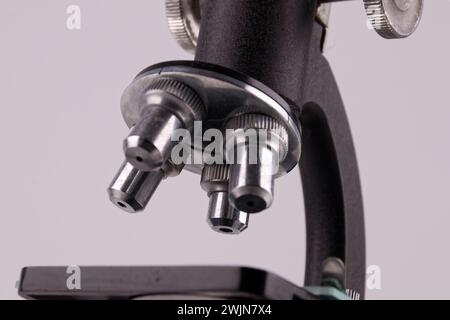 an old microscope stands on a white surface with real shadows, close up Stock Photo
