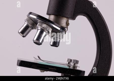 an old microscope stands on a white surface with real shadows, close up Stock Photo