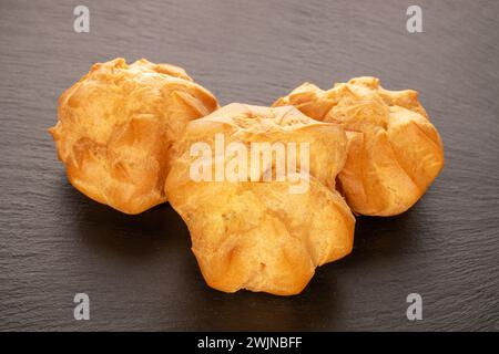 Three delicious éclairs on slate stone, macro. Stock Photo