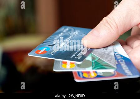 Russia Rzhev Tver region March 14, 2021 Male fingers are holding credit cards on a dark background. Offer to get bank cards. Stock Photo