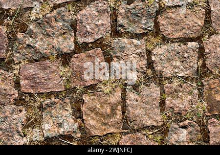 Fragment of a paved road. Background creative texture of brown stone pavement. Beautiful stone texture. Stock Photo