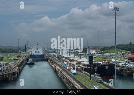 Panama Canal, Panama - July 24, 2023: Gatun locks at Atlantic side of canal under blue cloudscape. CMA CGM container vessel leaving, Nord Bering bulk Stock Photo