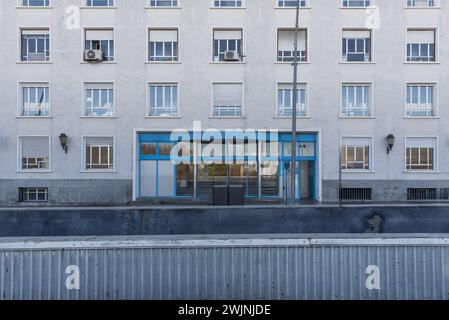 Facade of a building with many square windows and a large metal portal painted blue Stock Photo