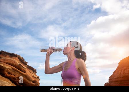 sporty woman drinking water from a bottle, thirsty after exercise. Stock Photo