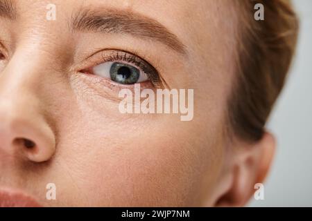 close up of appealing woman with blonde hair looking at camera with contact lense on her eye Stock Photo
