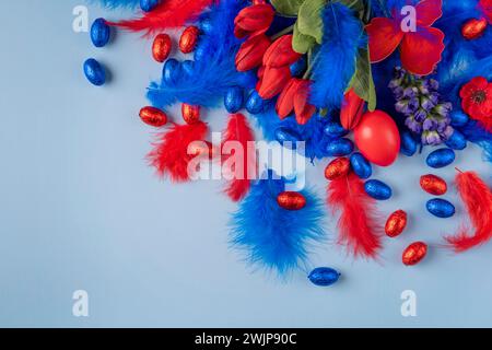 Blue and red arrangement of tulips, feathers and Easter eggs on a light blue background Stock Photo
