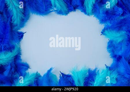Frame made of blue and turquoise feathers on a light blue background Stock Photo