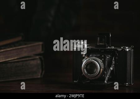 Vintage camera on a dark background next to old books Stock Photo