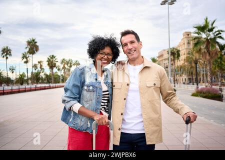 Portrait of cheerful middle-aged multiracial tourist couple embraced together look smiling at camera Stock Photo