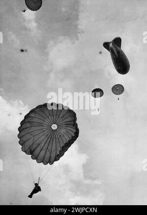 Britain Trains Her New Airborne Army -- Airborne Trainees jump 700 feet from a balloon at the upper Heyford training school, near Oxford. Though the glories of Arnhem have gone of brighten history's pages and most members of the war-time airborne forces have scattered to their civilian jobs, parachutists and other airborne troops will have a foremost place in Britain's army of the future. At the Airborne Forces Depot, Aldershot, and the Royal Air Force Parachute and glider Training school at Upper Heyford (Oxfordshire), volunteers are under strict training for the airborne units of the Reg ... Stock Photo