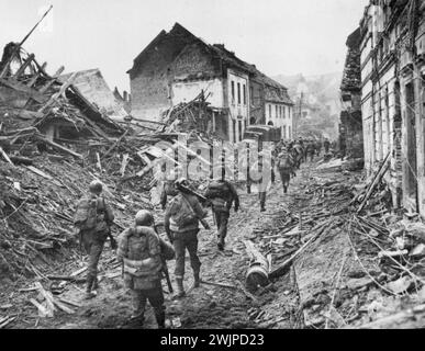 Ninth Army Infantrymen Advance -- Infantrymen of U.S. Ninth Army Advance Through the ravaged town of Linnich, Germany, After crossing the Roer River in their current offensive. March 5, 1945. (Photo by Associated Press Photo). Stock Photo