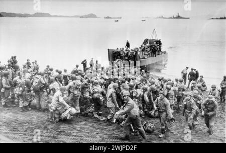 Kiska Invaders Hustle Into Landing Craft At start Of Attack -- With large naval craft standing by in the background, Allied Troops Hustle in to formation as they are loaded in to shallow-draft boat on shore of an unidentified Aleutian Island for the start of the combined American and Canadian Land, sea and air attack which resulted in the capture of the once strong Jap North Pacific base. August 21, 1943. (Photo by AP Wirephoto). Stock Photo