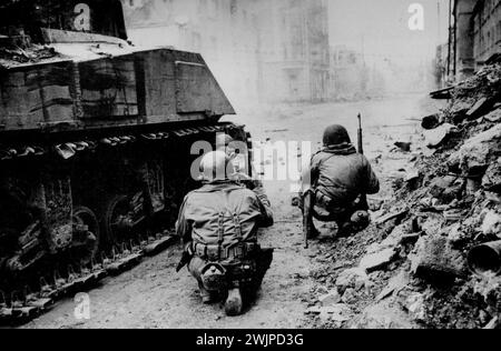 Third Army Men With Stoms into Coblenz -- Armour and infantrymen of general  petton's 3rd. Army stormed Coblenz and captured most of the city after fierce street battles. Here in an American tank firing ***** a street in the city while ***** take cover beside it from *****. May 21, 1945. (Photo by Sport & General Press Agency, Limited). Stock Photo