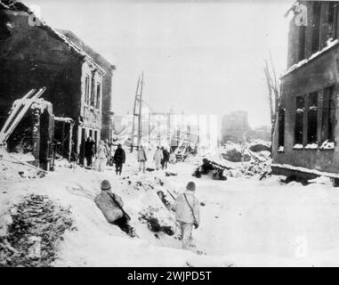 Wrecked St. Vith In Black and White -- U. S. Troops of the first Army, Garbed in Camouflage snow suits, reconnoiter in the snow-covered Streets and blackened houses of St. Vith, Belgium, after the city was captured from the German Forces. January 31, 1945. (Photo by AP Wirephoto). Stock Photo