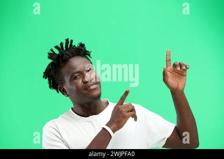 Man, close-up, on a green background, pointing up. Stock Photo
