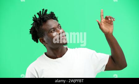 Man, close-up, on a green background, pointing up. Stock Photo