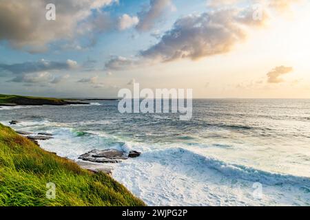 Spectacular sunset view of Mullaghmore Head with huge waves rolling ashore. Picturesque scenery with rocky coastline in evening light. Signature point Stock Photo