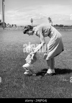 Farm worker's wife teaching her baby girl to walk, FSA (Farm Security Administration) labor camp, Caldwell, Idaho, USA, Russell Lee, U.S. Farm Security Administration, June 1941 Stock Photo