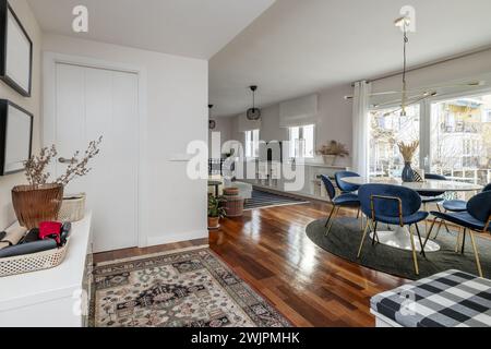 Entrance to a living room of a house with a circular dining table, exit to a terrace and some aluminum windows on the wall Stock Photo