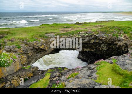 Fairy bridges, impressive stone arches near Tullan Strand, one of Donegals surf beaches, framed by a scenic back drop provided by the Sligo-Leitrim Mo Stock Photo