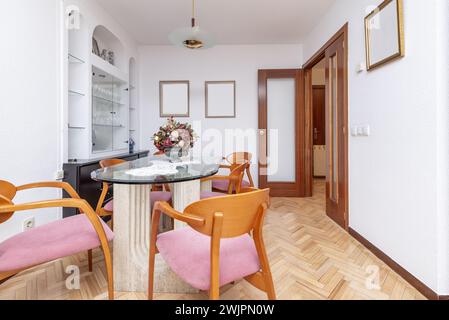 Living room of a house with a glass dining table with marble feet and cherry wood chairs Stock Photo