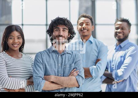 Group of professionals in businesswear, smiling and standing with arms crossed in office. Stock Photo
