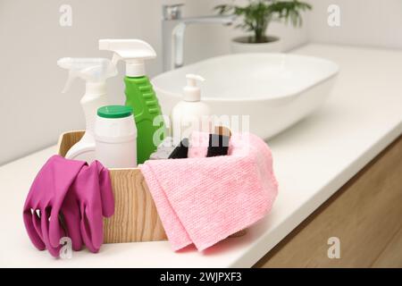 Different cleaning products in wooden box on countertop indoors Stock Photo