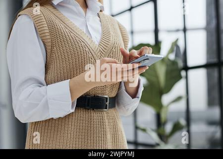 Cheerful student woman sitting at table break holding mobile phone surfing internet Stock Photo