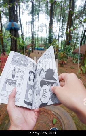 Photo of an Asian woman reading a comic book in Indonesian Stock Photo