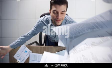 A male office worker is scattering papers. Stock Photo