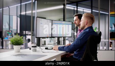 Accountants Looking At Invoice Spreadsheet On Computer Monitor Stock Photo