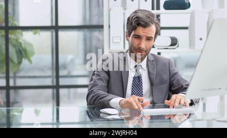 Man looking at computer monitor while sitting in modern office Stock Photo