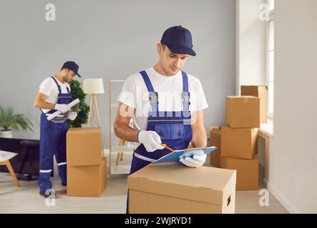 Workers of moving service working in new apartment delivering cardboard boxes Stock Photo