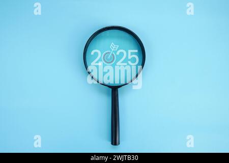 Magnifying glass and targets 2025. Concept of new year 2025, beginning of success, challenge or career path, change, planning, goals, challenges and n Stock Photo