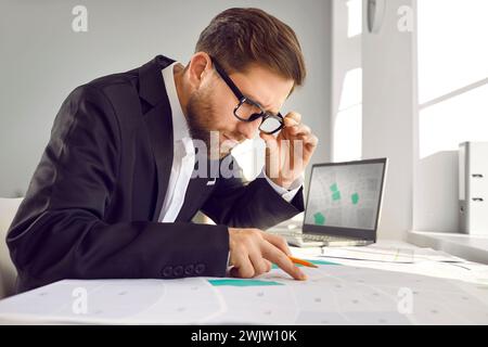 Professional cartographer working with printed cadastral map at table on his workplace. Stock Photo