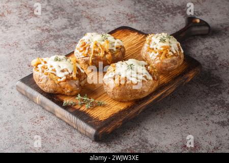 Whole baked jacket potatoes stuffed with French onions and Gruyere cheese close-up in a bowl on the table. Horizontal Stock Photo