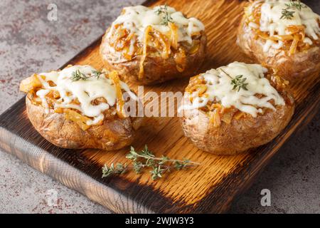 Baked jacket potatoes stuffed with caramelized onions and Gruyere cheese close-up in a bowl on the table. Horizontal Stock Photo