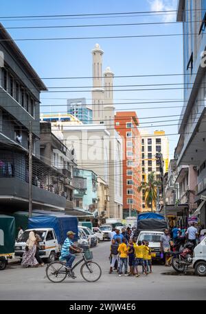 A man cyclkes past a group of boys in this general view of life in a street in central Dar es Salaam, Tanzania. Stock Photo