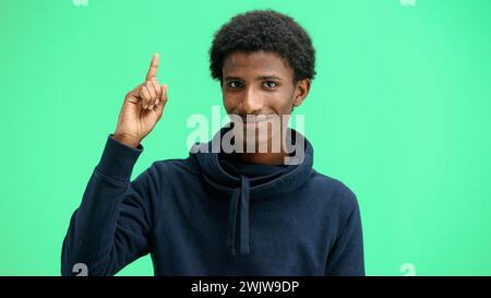 Man, close-up, on a green background, pointing up Stock Photo