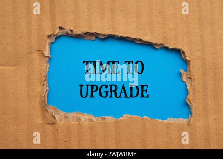 Time to upgrade words written on torn cardboard paper with blue background. Conceptual symbol. Copy space. Stock Photo